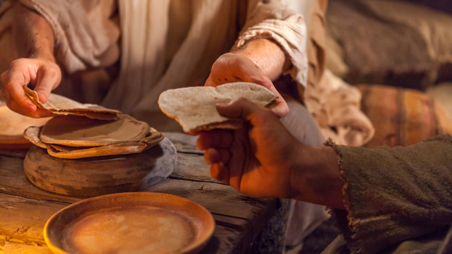 A person breaks bread and hands it to someone. Bread is one example of Passover imagery Jesus Christ used in his "Bread of Life" sermon. Image courtesy churchofjesuschrist.org