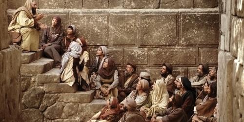 Paul sits and teaches a group of men and women. Image from Bible Videos of The Church of Jesus Christ of Latter-day Saints.